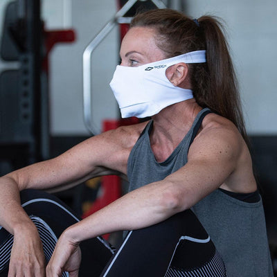 White Play Safe Face Mask Lifestyle Image – Female Model Wearing Protective Safety Face Mask in the Gym while Sitting Down - Left Angle