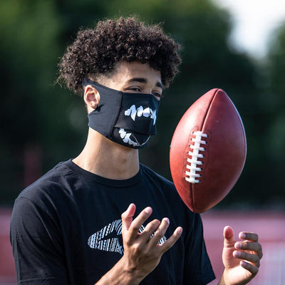 Black White Fang Play Safe Face Mask – Male Football Player Wearing Protective Safety Face Mask while Spinning Football - Right Angle